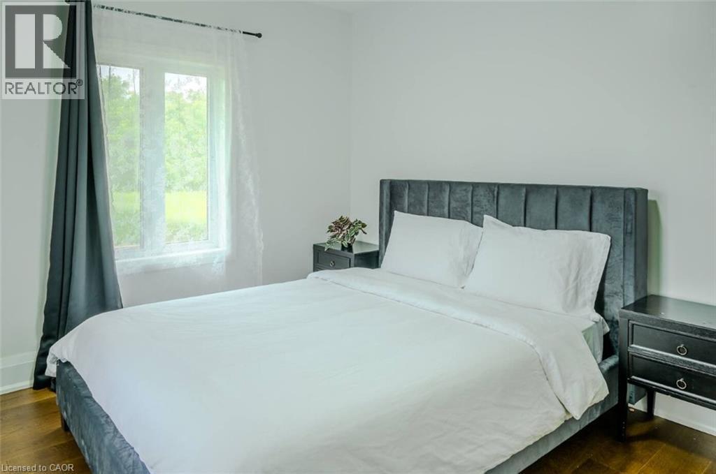 Hardwood flooring, white painted walls, and a window with sheer and solid drapes - 107 6Th Line Line, Haldimand, ON - Indoor Photo Showing Bedroom