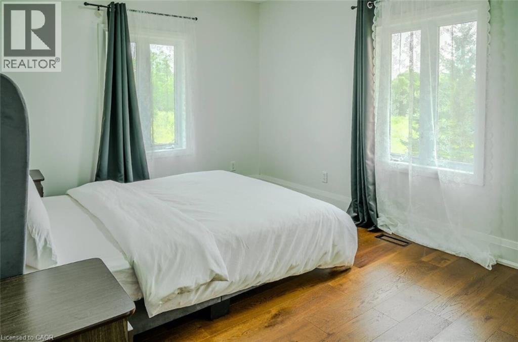 Hardwood flooring throughout, featuring two large windows with white trim, and white wall finishes - 107 6Th Line Line, Haldimand, ON - Indoor Photo Showing Bedroom