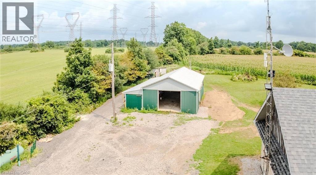 Gravel driveway leading to an expansive metal-sided barn with a white roof - 107 6Th Line Line, Haldimand, ON - Outdoor With View