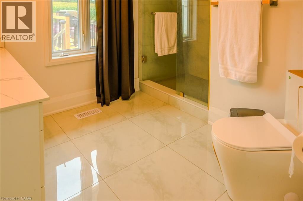 White tile flooring, glass-enclosed shower, white vanity with countertop, modern toilet - 107 6Th Line Line, Haldimand, ON - Indoor Photo Showing Bathroom
