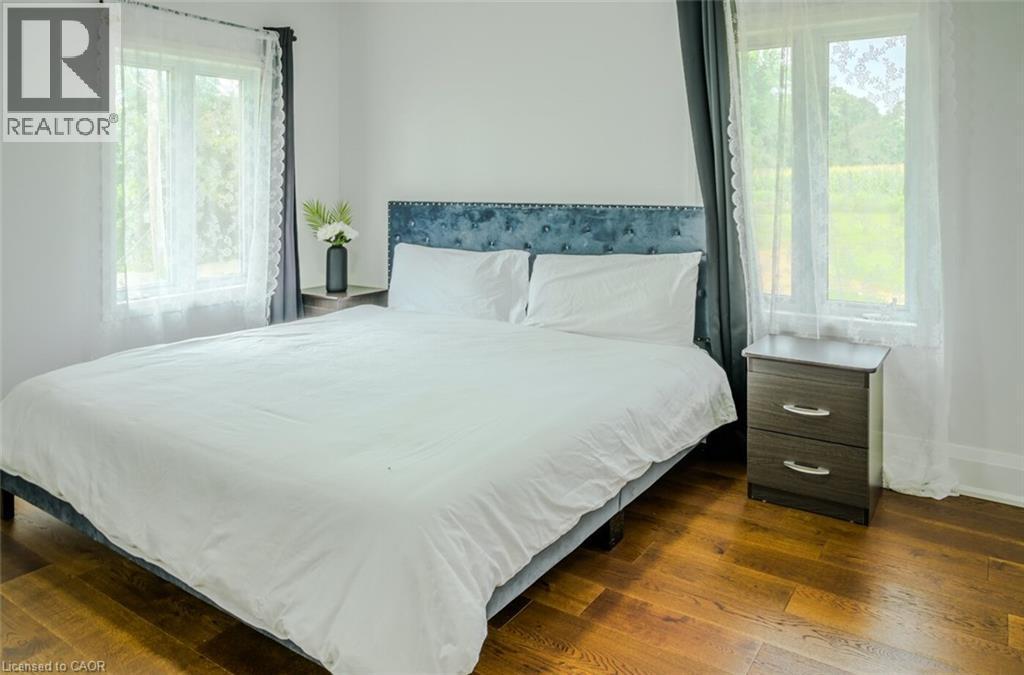 Hardwood flooring throughout, bright white walls, and a tufted fabric headboard - 107 6Th Line Line, Haldimand, ON - Indoor Photo Showing Bedroom