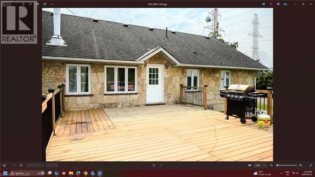 Exterior stone cladding, asphalt shingle roofing, white paneled door, and a spacious wooden deck with railing - 107 6Th Line Line, Haldimand, ON - Outdoor