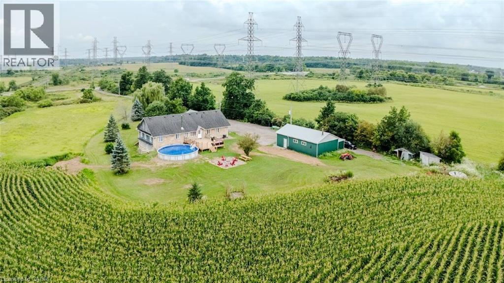 Expansive rural property featuring a primary residence with a deck, a circular above-ground pool, a detached green outbuilding, and surrounding cultivated fields - 107 6Th Line Line, Haldimand, ON - Outdoor With View