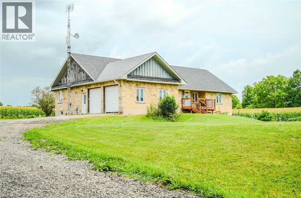 Stone exterior with shingle roofing, integrated two-car garage with white doors, and a wooden deck - 107 6Th Line Line, Haldimand, ON - Outdoor