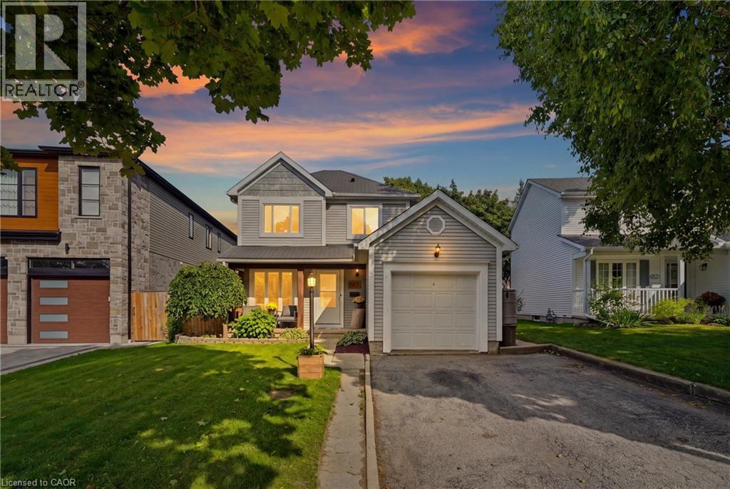 Two-story property with light gray siding, an attached single-car garage, and a covered front porch featuring recessed lighting and a lantern-style fixture - 563 Westvale Drive, Waterloo, ON - Outdoor With Facade