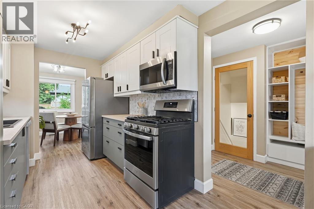 Stainless steel appliances, wood-finish flooring, white upper cabinetry, gray lower cabinetry, and a light-colored countertop - 563 Westvale Drive, Waterloo, ON - Indoor Photo Showing Kitchen With Upgraded Kitchen