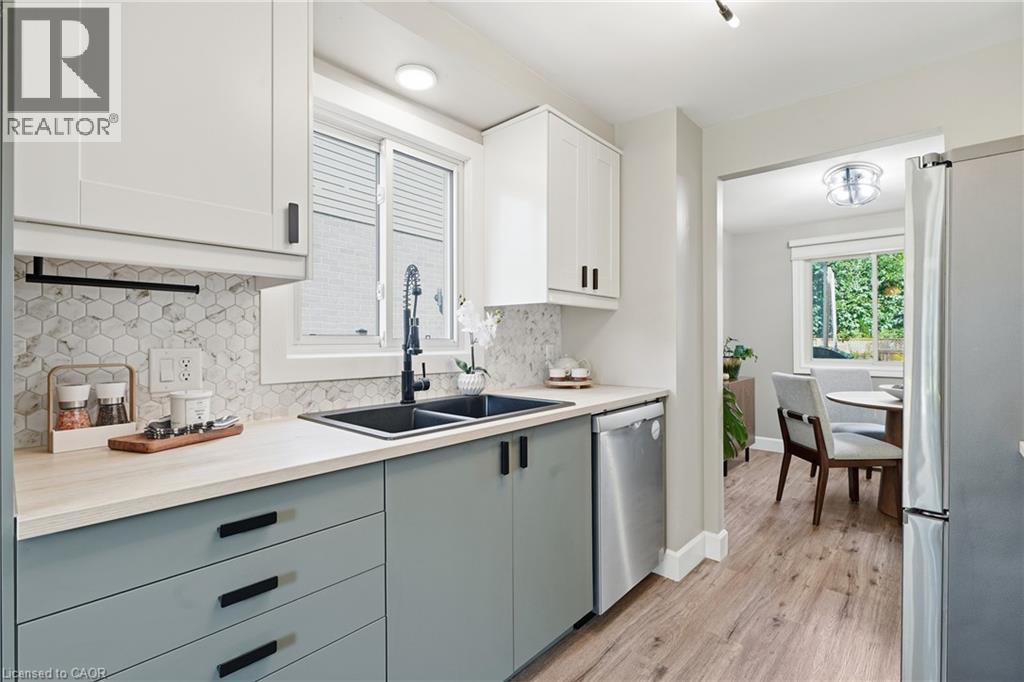 Kitchen featuring two-tone cabinetry, hexagon tile backsplash, and wood-finish flooring - 563 Westvale Drive, Waterloo, ON - Indoor Photo Showing Kitchen With Double Sink With Upgraded Kitchen