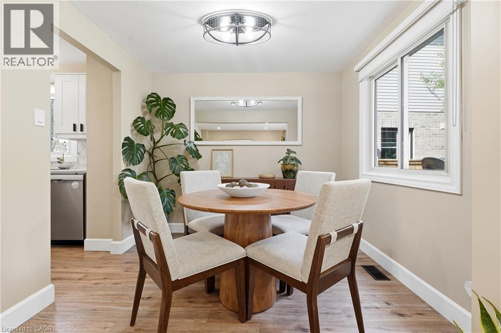 Wood-finish flooring, recessed lighting, white trim, and a built-in kitchen featuring white cabinetry and stainless steel appliances - 563 Westvale Drive, Waterloo, ON - Indoor Photo Showing Dining Room