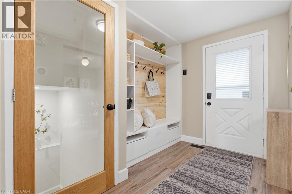 Built-in storage bench with shelving and coat hooks, wood-finish flooring, and an exterior door with integrated blinds - 563 Westvale Drive, Waterloo, ON - Indoor Photo Showing Other Room