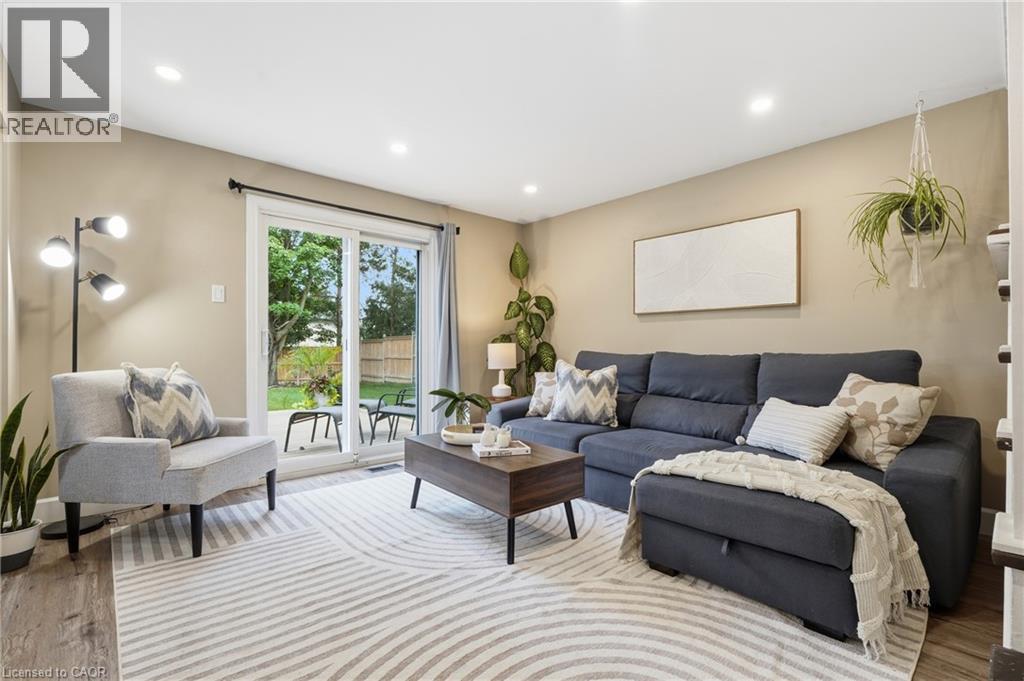 Recessed ceiling lighting, wood-finish flooring, and a sliding glass door providing access to an outdoor patio - 563 Westvale Drive, Waterloo, ON - Indoor Photo Showing Living Room