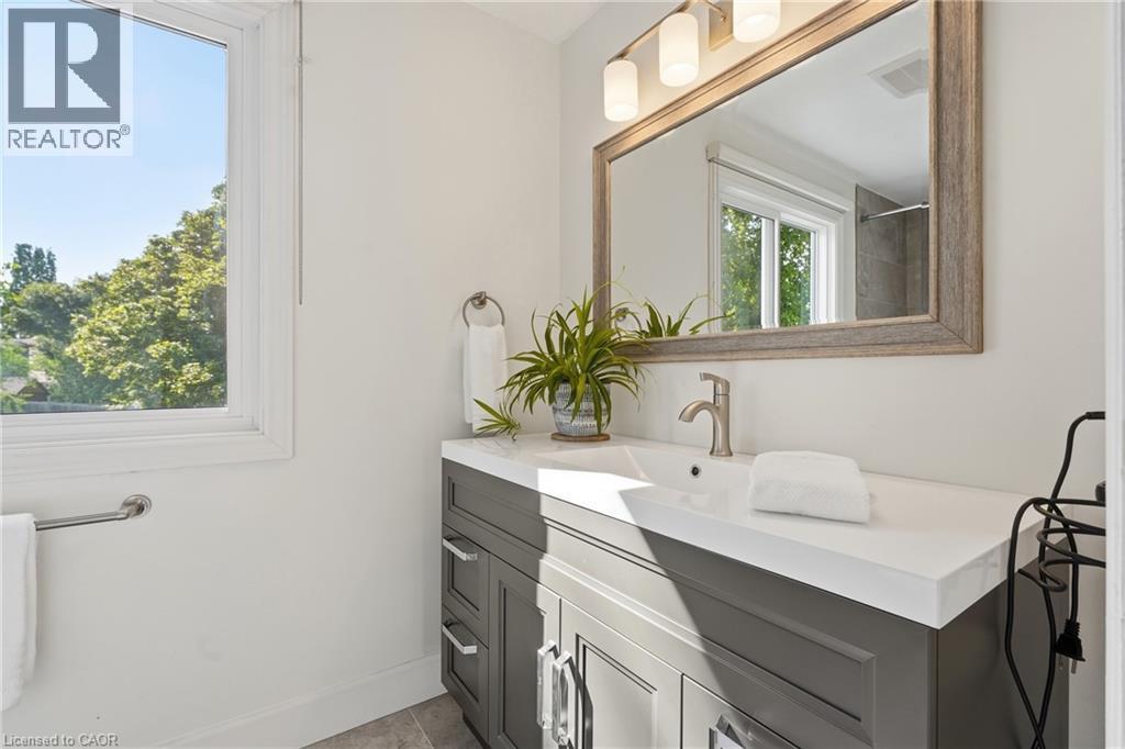 White wall paint, large window, vanity with white countertop, integrated sink, and brushed nickel faucet - 563 Westvale Drive, Waterloo, ON - Indoor Photo Showing Bathroom