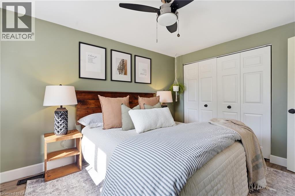 Recessed lighting, ceiling fan, wood-finish flooring, paneled closet doors, and a wood accent wall - 563 Westvale Drive, Waterloo, ON - Indoor Photo Showing Bedroom