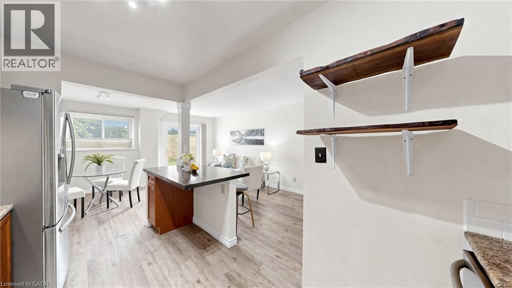 Wood-finish flooring, stainless steel refrigerator, kitchen island with dark countertop, and decorative wall shelving - 304 Bluevale Street N, Waterloo, ON - Indoor