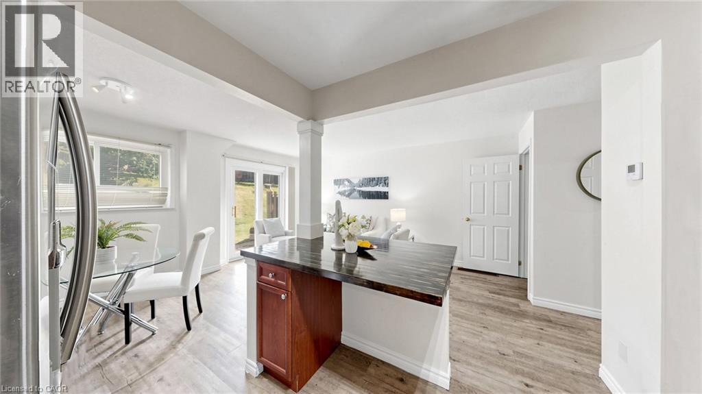 Open-concept living space featuring wood-finish flooring, a kitchen island with storage, and french doors leading to the outdoor area - 304 Bluevale Street N, Waterloo, ON - Indoor