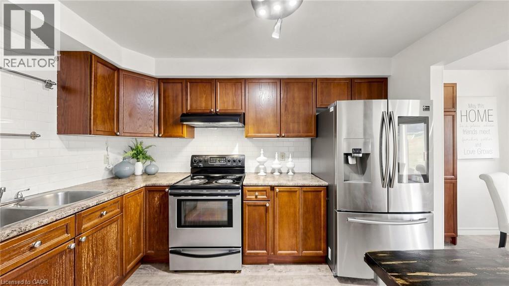 Kitchen featuring wood cabinetry, stainless steel appliances, white subway tile backsplash, and a double basin sink - 304 Bluevale Street N, Waterloo, ON - Indoor Photo Showing Kitchen