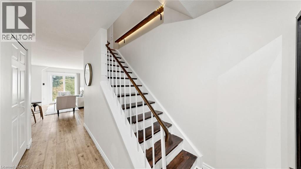 Hardwood flooring throughout, white painted walls, white trim, and a staircase with dark wood treads and a wood handrail - 304 Bluevale Street N, Waterloo, ON - Indoor Photo Showing Other Room