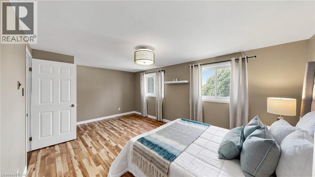 Wood-finish flooring, neutral wall tones, and two windows with natural light - 304 Bluevale Street N, Waterloo, ON - Indoor Photo Showing Bedroom