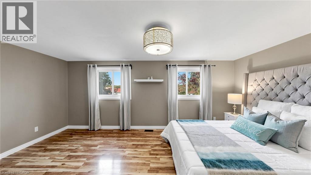 Wood-finish flooring, two windows, and a decorative ceiling light fixture - 304 Bluevale Street N, Waterloo, ON - Indoor Photo Showing Bedroom