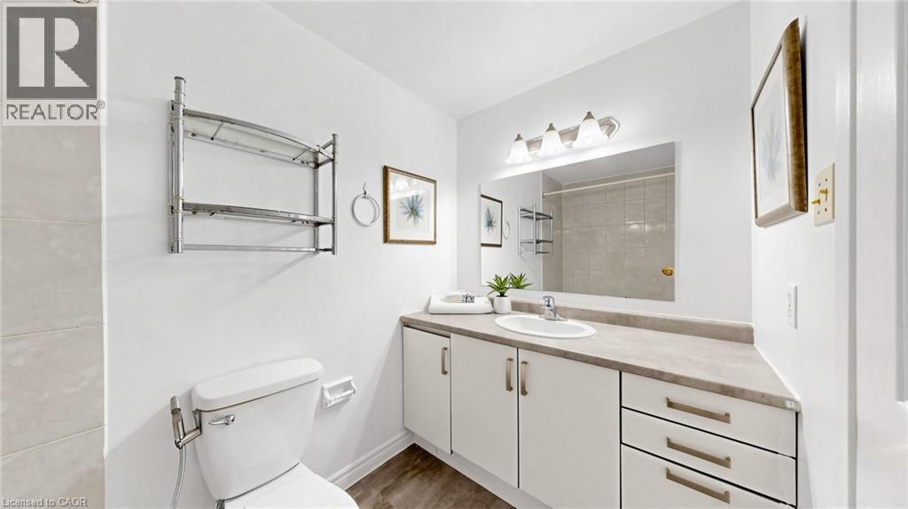 White vanity with integrated sink, rectangular mirror, and three-light fixture - 304 Bluevale Street N, Waterloo, ON - Indoor Photo Showing Bathroom