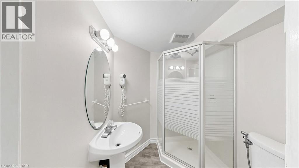 Pedestal sink with chrome faucet, oval wall mirror, and vanity lighting - 304 Bluevale Street N, Waterloo, ON - Indoor Photo Showing Bathroom