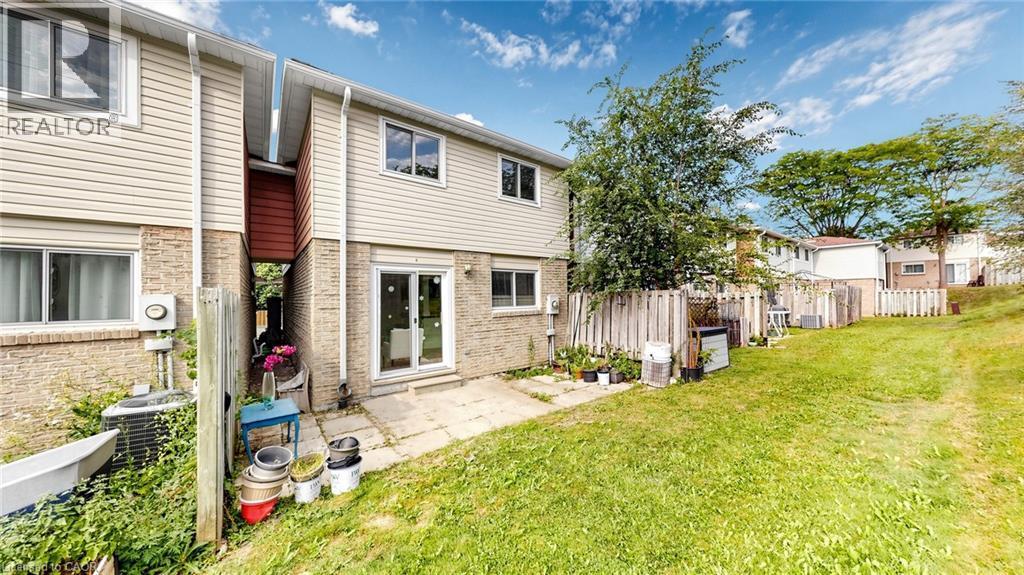 Rear exterior featuring brick and siding construction, ground-level patio, and sliding glass door access - 304 Bluevale Street N, Waterloo, ON - Outdoor