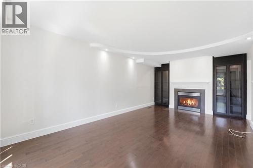 Wood-finish flooring, recessed lighting, built-in display cabinetry, and a fireplace with a stone mantel - 23 Heatherdale Place, Hamilton, ON - Indoor With Fireplace