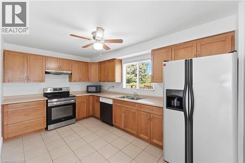 Light wood-finish cabinetry, stainless steel range with overhead ventilation, undermount double-basin sink, and tiled flooring - 23 Heatherdale Place, Hamilton, ON - Indoor Photo Showing Kitchen With Double Sink