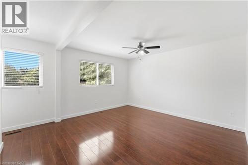Expansive room featuring wood-finish flooring, two windows with horizontal blinds, and a ceiling fan with integrated lighting - 23 Heatherdale Place, Hamilton, ON - Indoor Photo Showing Other Room