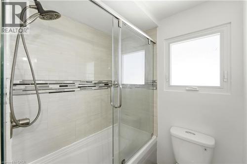 Bathtub with sliding glass shower door, tiled shower surround with decorative mosaic accent, and a shower head with hose attachment - 23 Heatherdale Place, Hamilton, ON - Indoor Photo Showing Bathroom