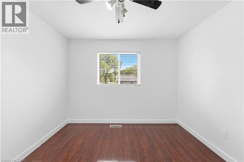 Wood-finish flooring, white painted walls, window with blinds, and a ceiling fan with integrated lighting - 23 Heatherdale Place, Hamilton, ON - Indoor Photo Showing Other Room
