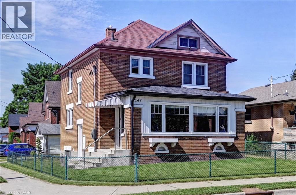 Brick exterior with a red shingle roof, featuring white trim and a prominent bay window - 147 Courtland Avenue E, Kitchener, ON - Outdoor With Facade