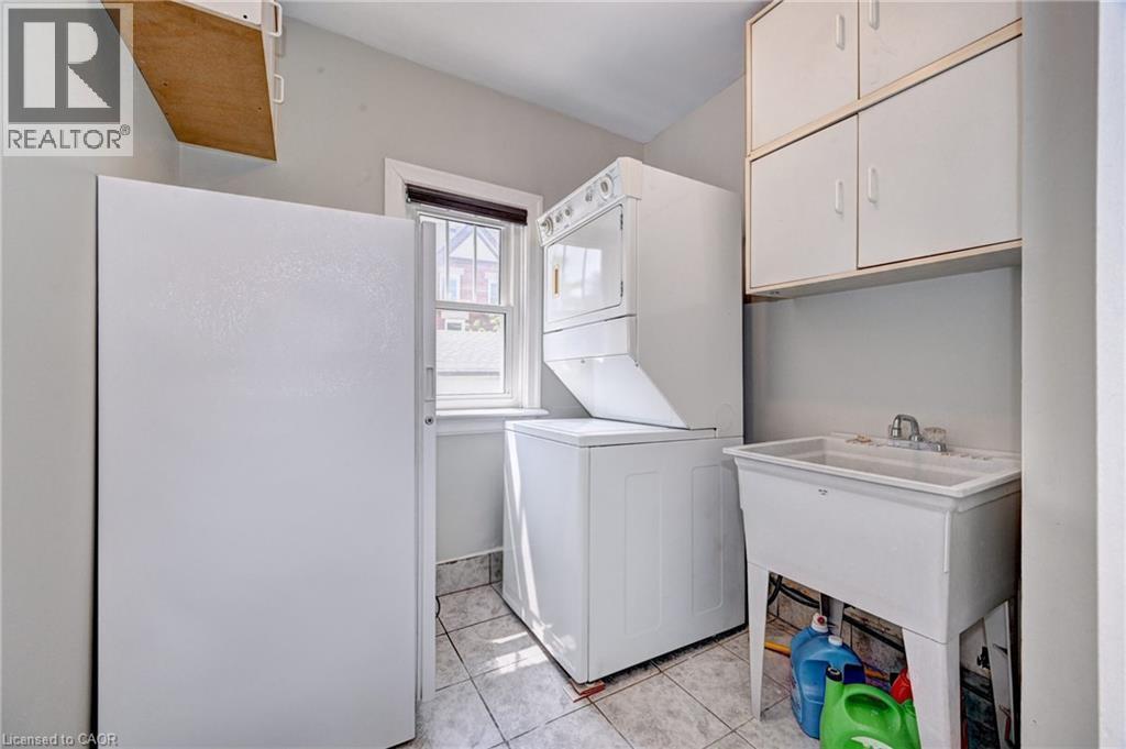 Laundry area featuring a utility sink, wall-mounted cabinetry, a window, and tile flooring - 147 Courtland Avenue E, Kitchener, ON - Indoor Photo Showing Laundry Room