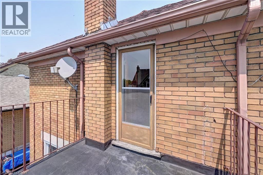 Brown brick exterior featuring a flat roofline, metal railings, and a glass-paneled door - 147 Courtland Avenue E, Kitchener, ON - Outdoor With Exterior