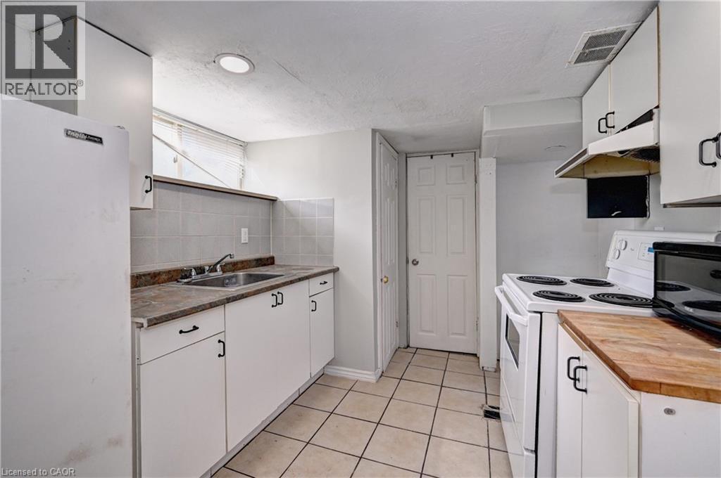 Kitchen featuring white cabinetry with dark hardware, a stainless steel sink, and a white refrigerator - 147 Courtland Avenue E, Kitchener, ON - Indoor Photo Showing Kitchen