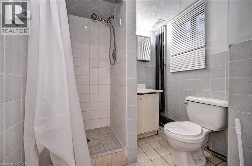 Full bathroom featuring a walk-in shower with tiled walls and floor, a toilet, a vanity with a base cabinet, and a wall-mounted medicine cabinet - 147 Courtland Avenue E, Kitchener, ON - Indoor Photo Showing Bathroom