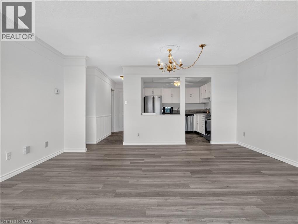 Wood-finish flooring throughout, crown molding detailing, and a chandelier with ceiling medallion - 7 Gale Crescent Unit# 1107, St. Catharines, ON