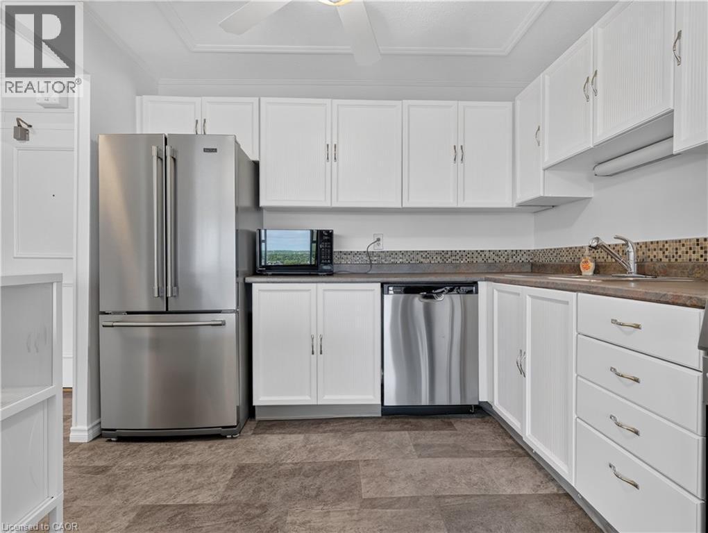Stainless steel appliances, white cabinetry, integrated sink, mosaic tile backsplash, and durable flooring - 7 Gale Crescent Unit# 1107, St. Catharines, ON