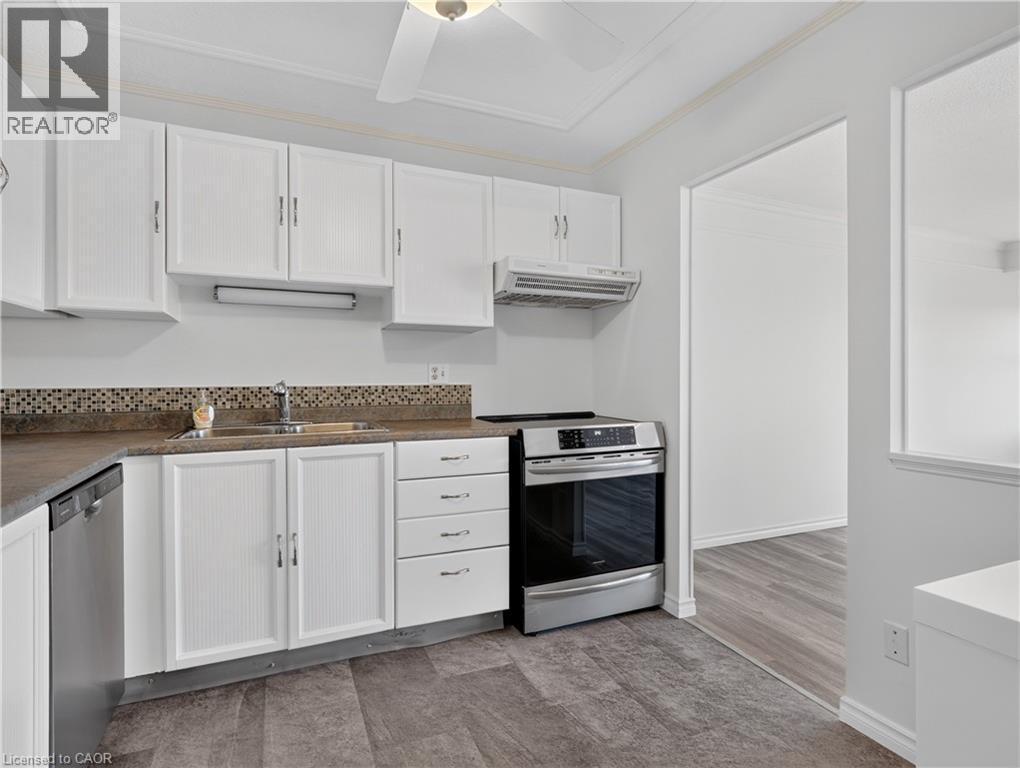 Kitchen featuring white cabinetry, mosaic tile backsplash, wood-finish flooring, stainless steel dishwasher, and stainless steel range - 7 Gale Crescent Unit# 1107, St. Catharines, ON
