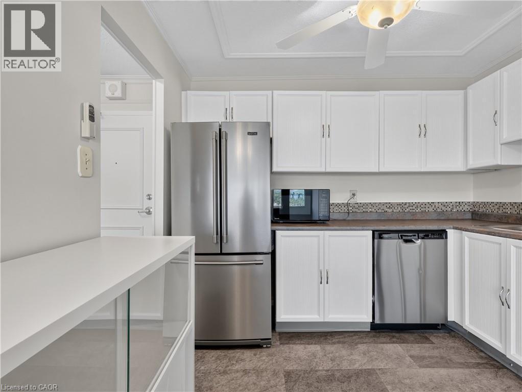 Kitchen featuring white cabinetry, stainless steel appliances, mosaic tile backsplash, and a ceiling fan with integrated lighting - 7 Gale Crescent Unit# 1107, St. Catharines, ON
