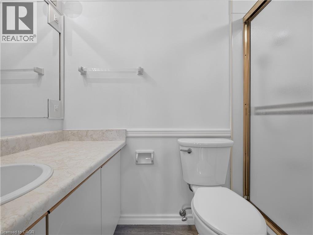 Vanity with integrated sink, solid surface countertop, white cabinetry, and wall-mounted mirror - 7 Gale Crescent Unit# 1107, St. Catharines, ON