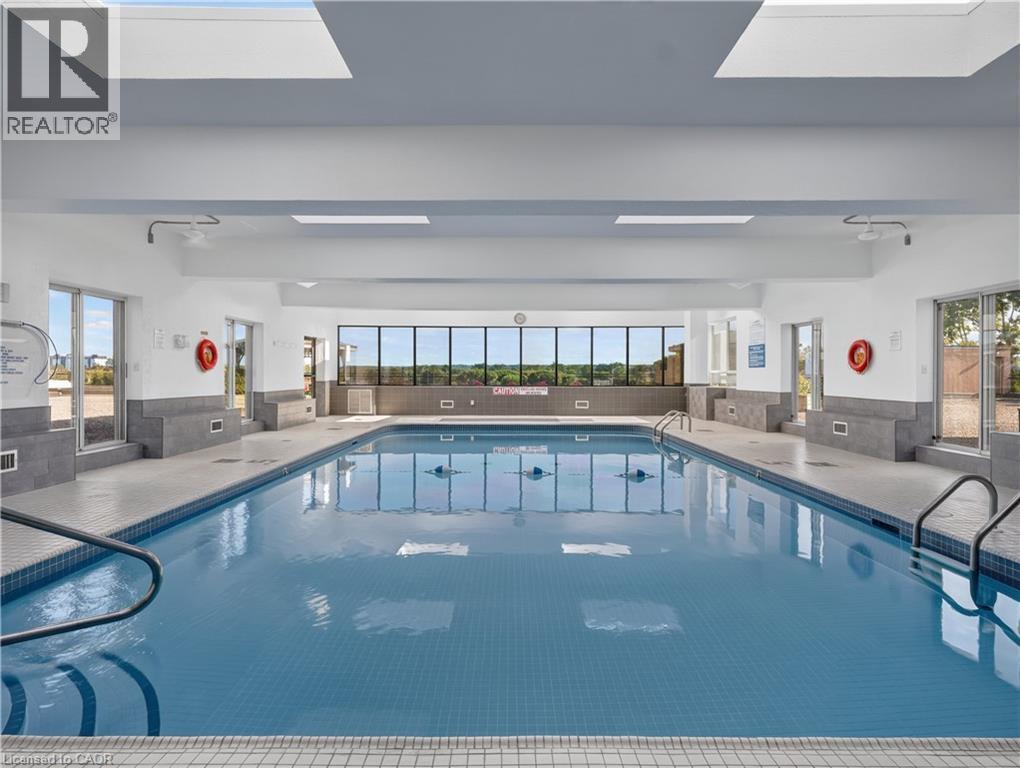Indoor swimming pool with blue mosaic tile, multiple skylights, and expansive exterior-facing windows - 7 Gale Crescent Unit# 1107, St. Catharines, ON