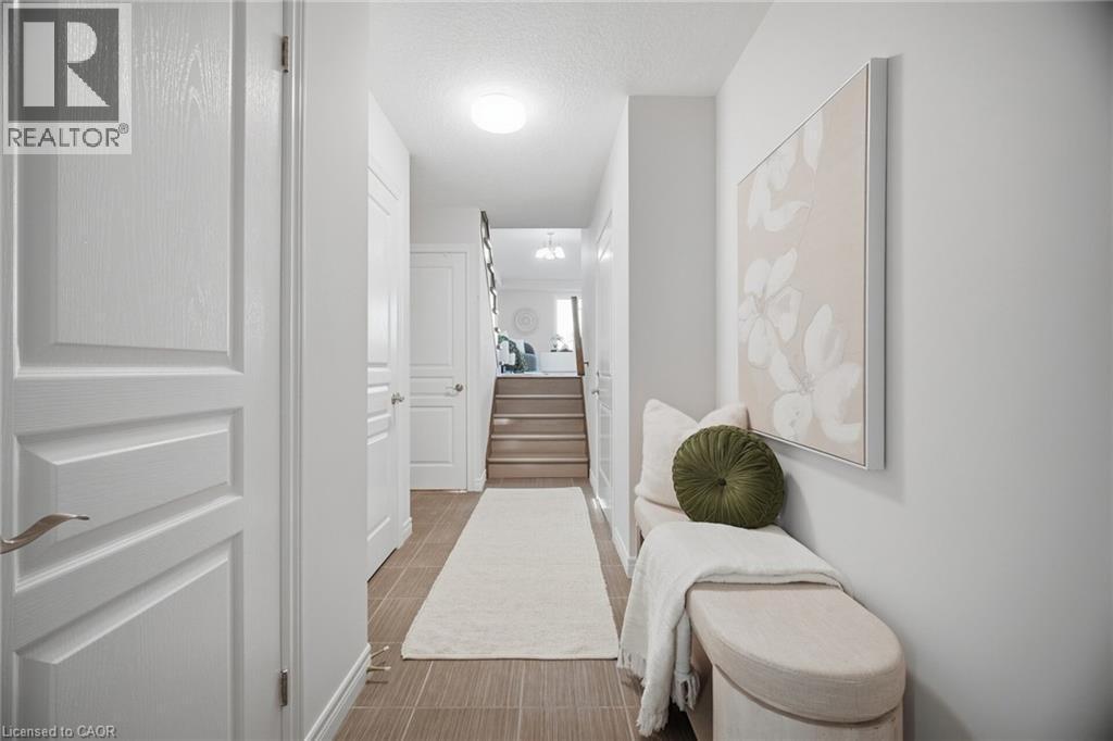 Tiled flooring, white paneled doors, light neutral wall color, and a staircase with wood-finish treads - 98 Bloom Crescent, Stoney Creek, ON
