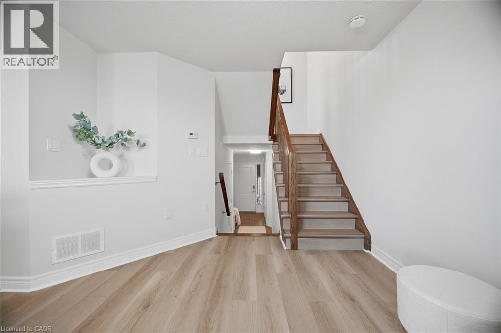 Wood-finish flooring throughout, solid wood staircase with wood handrail, and crisp white wall finishes - 98 Bloom Crescent, Stoney Creek, ON