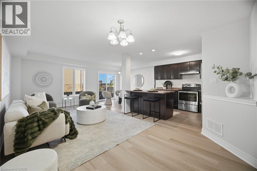 Open-concept living space featuring light wood-finish flooring, recessed lighting, and a kitchen island with seating - 98 Bloom Crescent, Stoney Creek, ON