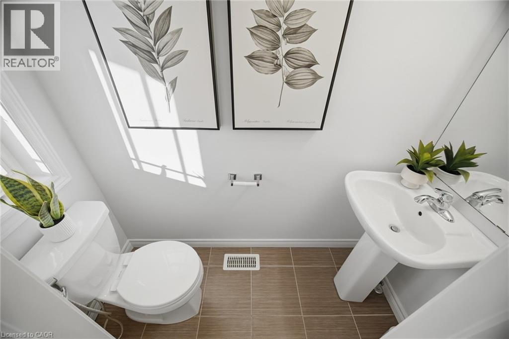 White pedestal sink with chrome faucet, white toilet, and tiled flooring - 98 Bloom Crescent, Stoney Creek, ON