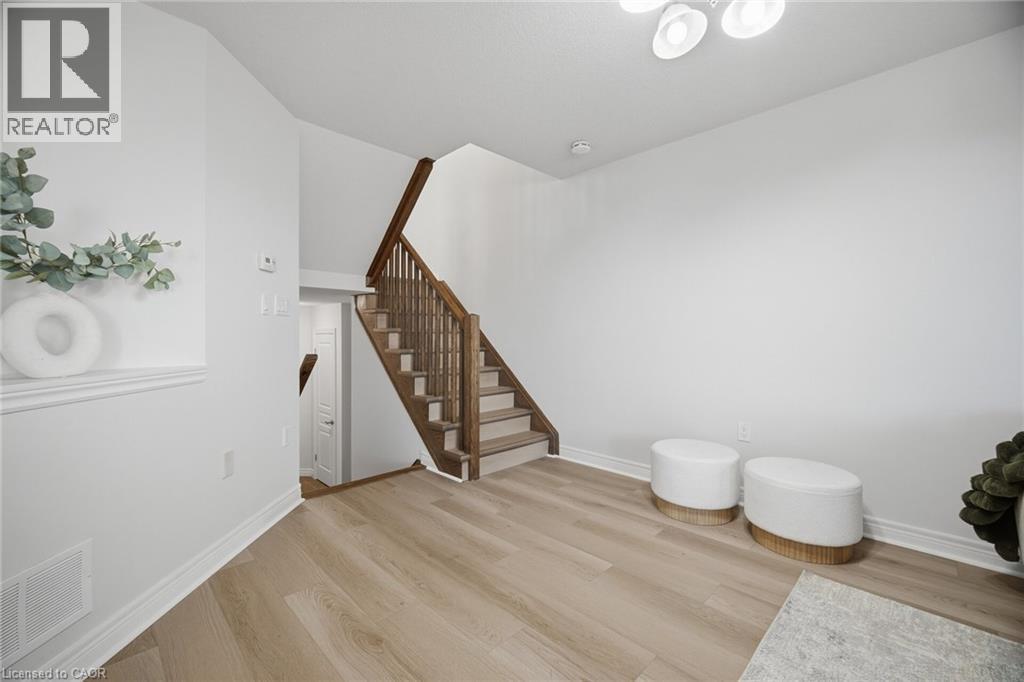 Wood-finish flooring, staircase with wood risers and railings, white painted walls, and overhead flush-mount lighting - 98 Bloom Crescent, Stoney Creek, ON
