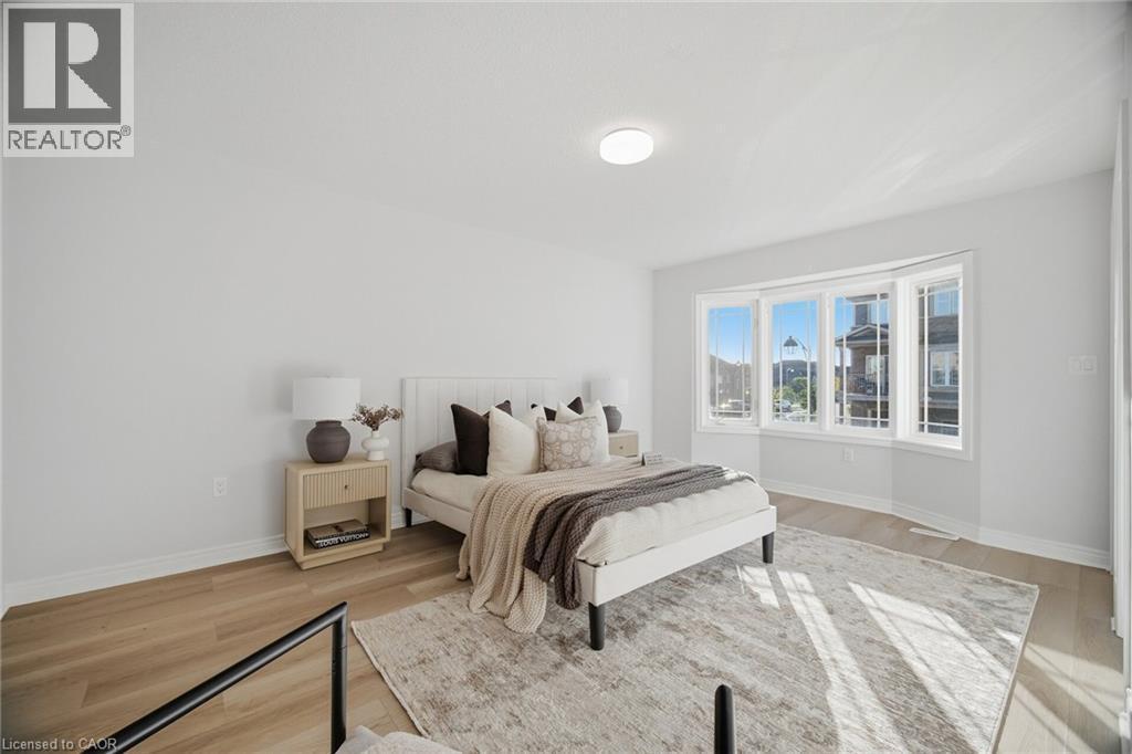 Bright room featuring a bay window, wood-finish flooring, recessed lighting, and a neutral color palette - 98 Bloom Crescent, Stoney Creek, ON