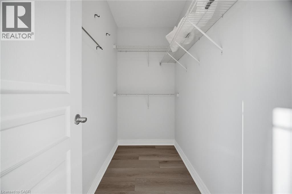 Walk-in closet featuring wood-finish flooring, white wire shelving, and a garment rod - 98 Bloom Crescent, Stoney Creek, ON