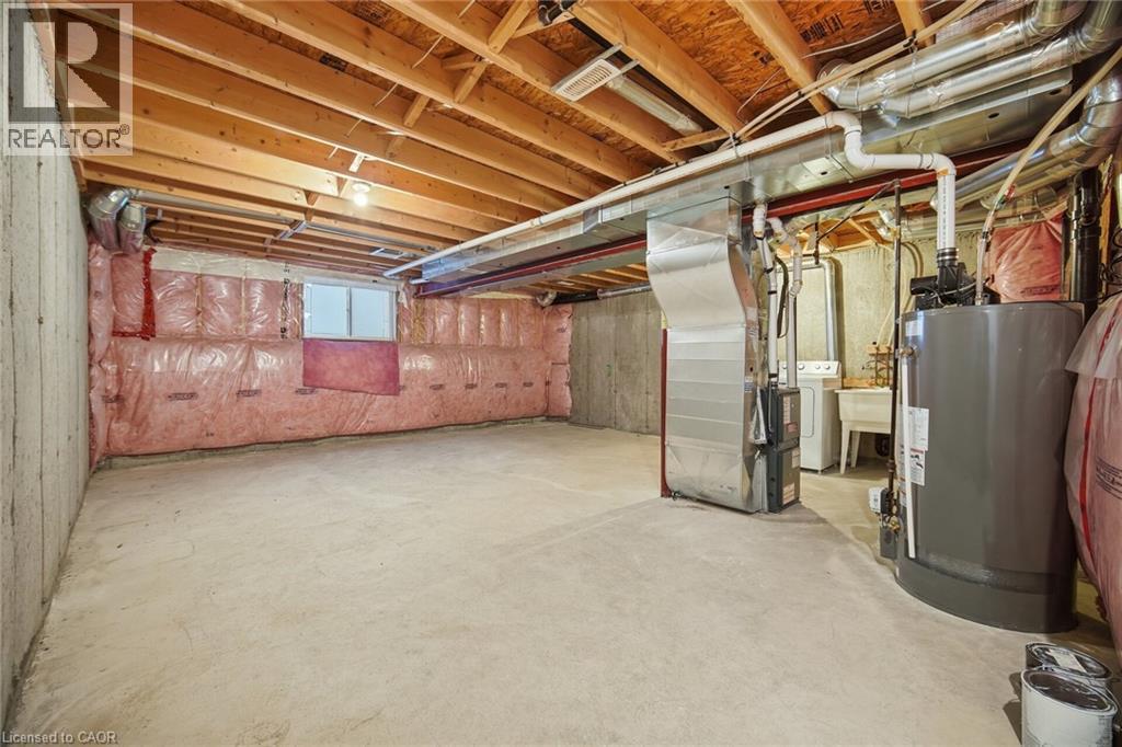 Unfinished basement featuring concrete flooring, exposed wood ceiling joists, insulated exterior walls, utility sink, and a water heater - 98 Bloom Crescent, Stoney Creek, ON