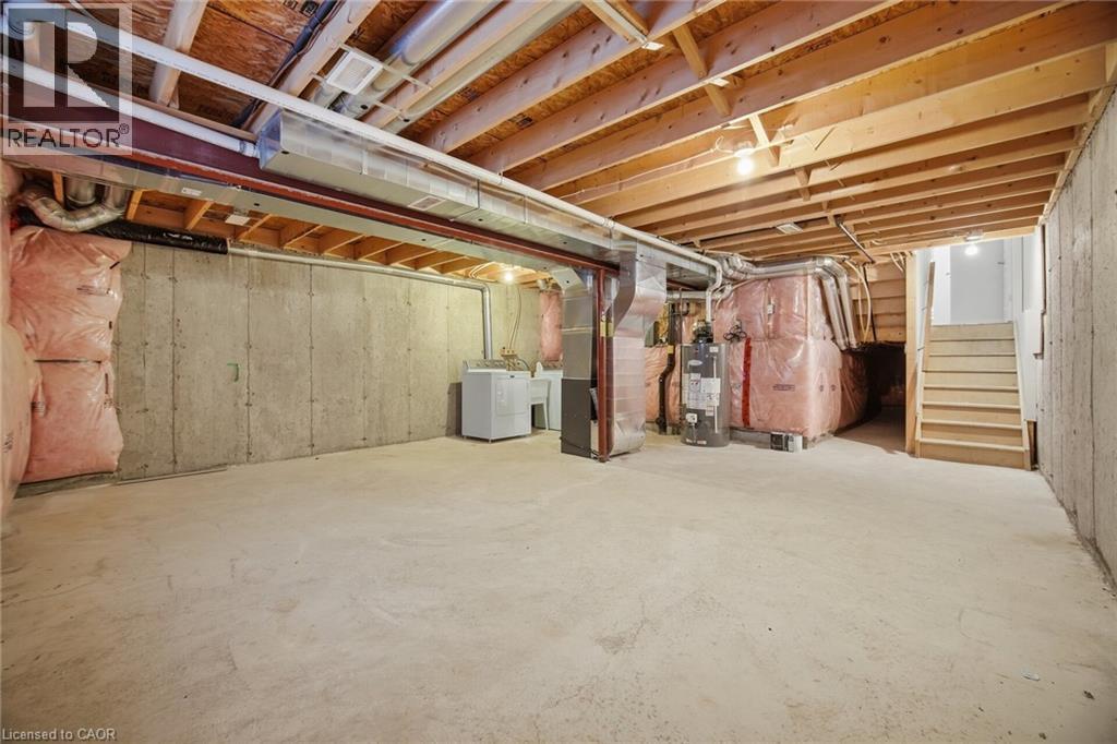 Unfinished basement featuring concrete flooring, exposed wood joists, utility sink, washer, and dryer - 98 Bloom Crescent, Stoney Creek, ON